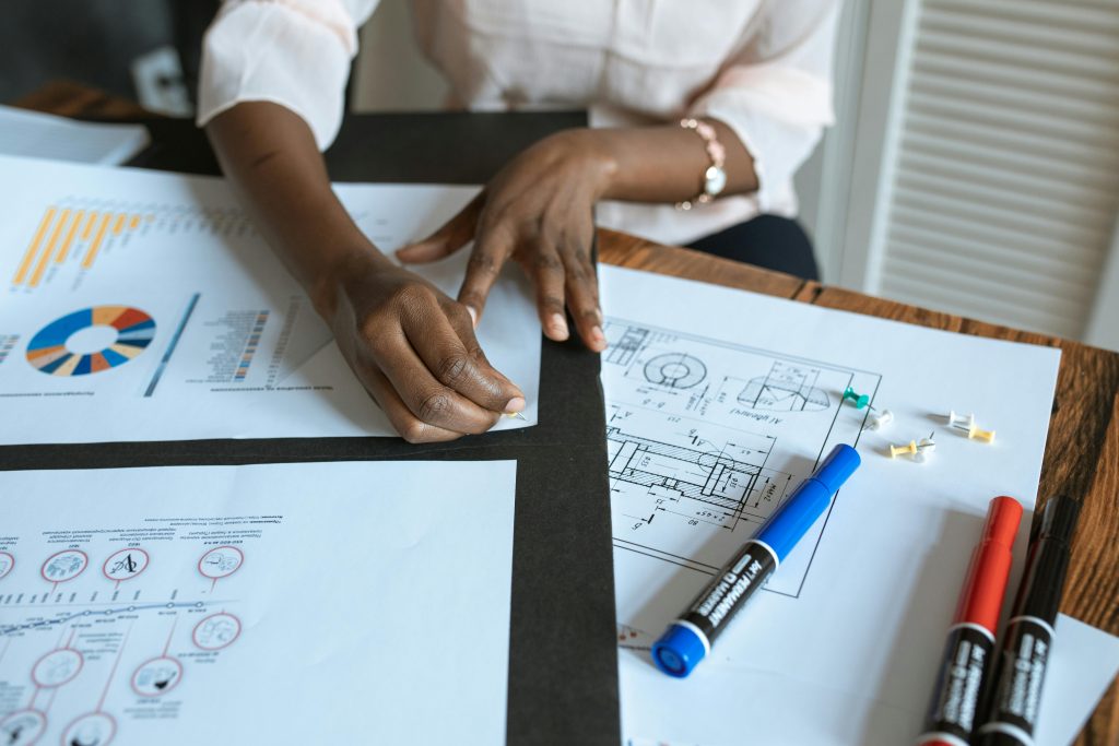 An adult working on business charts and design blueprints in an office setting.